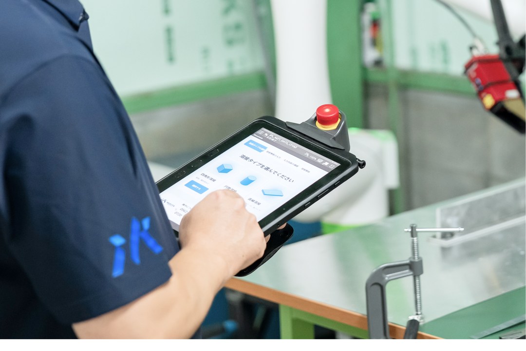 タブレットで協働ロボットを操作する作業者