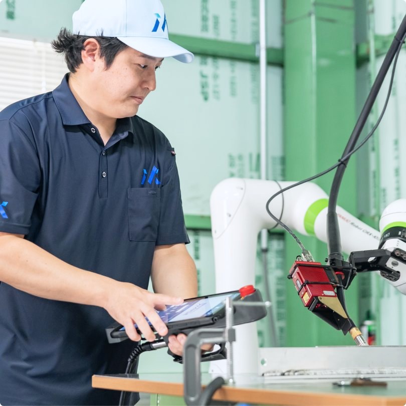タブレットを手にロボットの前に立つ作業者